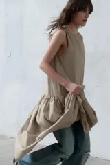 Vestido midi sin mangas de cuello redondo, con falda amplia con frunces y bolsillos laterales ocultos. Presenta cierre en la espalda con abertura y botón.