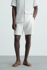 Bermuda azul marino de corte regular fit, confeccionada en tejido de algodón y lino. Cuenta con bolsillos frontales y traseros, cierre frontal con cremallera y botón.