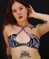 Top de bikini con estampado abstracto en blanco y negro, con tiras finas que se cruzan en el cuello y abertura en el centro del pecho.
