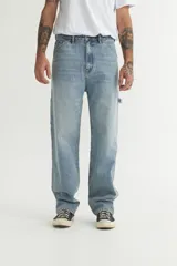 Pantalón de jean celeste de corte recto y holgado, con bolsillos laterales y traseros, y detalle de bolsillo tipo carpintero en la pierna.