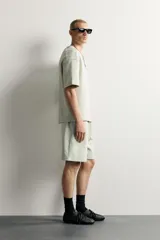 Bermuda estilo jogger de ajuste relajado, confeccionada en tejido interlock de algodón. Cuenta con cintura elástica ajustable con cordón, bolsillos frontales de vivo y diseño liso.