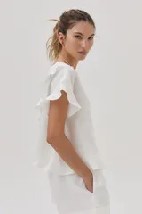 Blusa blanca de lino de manga corta, con volados en las mangas y espalda cruzada adornada con volados.