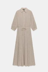 Vestido midi tipo camisero con estampado de cuadros, cuello solapa, manga corta con puño abotonado y cintura ajustable con lazada. Presenta detalle de godets en la falda y cierre frontal con botones ocultos.