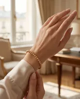 Pulsera esclava de acero con baño de oro, compuesta por pequeñas esferas metálicas unidas en un diseño elástico.