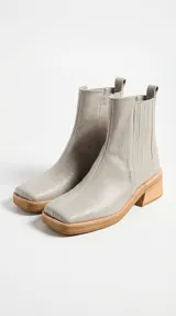 Bota tipo chelsea de cuero color suela, con paneles elásticos laterales, puntera cuadrada y suela de goma con taco de madera de diseño geométrico.