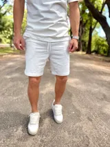 Conjunto deportivo blanco compuesto por una remera de manga corta de corte holgado y un short con cordón ajustable en la cintura.