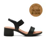 Sandalia de cuero negro con dos tiras anchas, una en el empeine con diseño trenzado y otra en el tobillo con ajuste elástico. Tiene taco bloque bajo y plantilla acolchada.