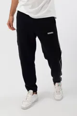 Pantalón de jogging negro con una franja vertical blanca a los costados y logo de la marca en la pierna izquierda.