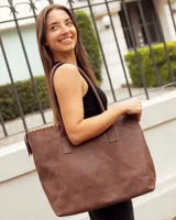 Bolso tipo tote de cuero vacuno color marrón caoba, con diseño artesanal que presenta costuras decorativas en el borde superior y asas fijas de hombro.