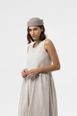 Vestido midi sin mangas de color beige, con silueta amplia y caída relajada, escote redondo y recortes frontales con volumen.