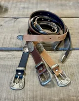 Cinto fino de cuero con hebilla metálica labrada y pasador con apliques metálicos circulares.