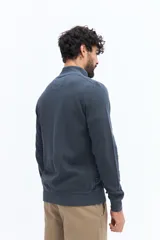 Campera de algodón color beige, estilo deportivo con cierre frontal, cuello alto y puños. Presenta bolsillos laterales y un pequeño logo bordado en el pecho.