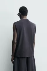 Camiseta sin mangas de corte relajado, confeccionada en tejido compacto de algodón con elasticidad, cuello redondo y diseño de sisa amplia.