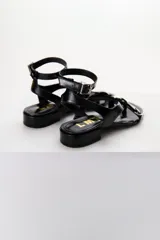 Sandalias de cuero color marrón chocolate, con tira ancha sobre el empeine con detalle de hebilla trenzada plateada, pulsera al tobillo con hebilla metálica y taco bajo cuadrado.