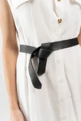 Cinturón de cuero negro, estilo lazo, con textura granulada y sin hebilla, diseñado para anudarse a la cintura.