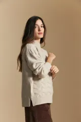 Sweater de punto color beige con diseño geométrico en relieve, cuello alto y mangas largas con puños acanalados.