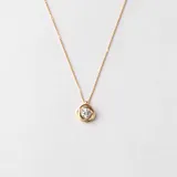 Conjunto compuesto por cadena fina y dije circular con circonia central engastada en oro 18k.