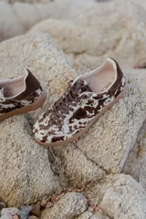 Zapatillas urbanas con capellada de cuero con estampado animal print en blanco y negro, detalles en gamuza negra, cordones negros y suela de goma.