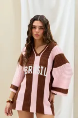 Remerón de punto oversize con diseño de rayas verticales en tonos marrón y rosado, cuello en V y moldería amplia. Presenta la inscripción "BRASIL" estampada en el frente.