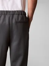 Pantalón de tejido grueso de punto liso con cintura elástica, corte ceñido y largo al tobillo. Presenta un diseño minimalista con logo de la marca bordado en el muslo.