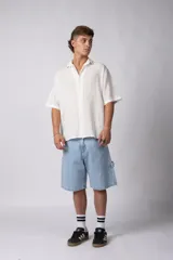 Camisa de hombre de manga corta color beige claro, confeccionada en lino. Tiene cuello clásico, cierre frontal con botones y corte recto.