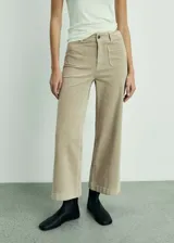 Pantalón tipo culotte de pana, color beige, con tiro alto, cierre de cremallera y botón, y bolsillos de parche delanteros y traseros.