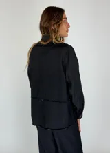 Chaqueta marrón con cuello camisero, cierre frontal con botones, bolsillos de parche y ruedo desflecado.