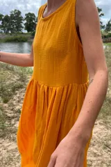 Vestido largo color amarillo de muselina de algodón, sin mangas, con corte fruncido en la cintura y falda amplia con movimiento.