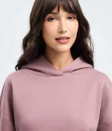 Buzo femenino de corte holgado, color malva, con capucha, manga larga con puños elásticos y bolsillo tipo canguro frontal.