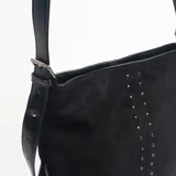 Cartera de hombro color negro, confeccionada en material tipo gamuza, con detalle de doble línea vertical de tachas metálicas en el frente y correas laterales ajustables con hebillas.