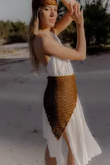 Bandana tejida a crochet con diseño triangular y terminaciones en cordones para anudar. Es un accesorio versátil que puede utilizarse como cinturón o como pañuelo para la cabeza.