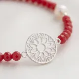 Pulsera de cuentas de cristal rojo con dije central circular de plata 925 calada y detalle de perla en el cierre.
