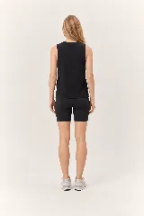 Conjunto deportivo de mujer compuesto por una musculosa blanca de cuello redondo con aberturas laterales y unos shorts biker negros ajustados de tiro alto con bolsillos laterales.