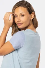 Remera de manga corta con cuello redondo y diseño de bloques de color. El cuerpo es beige, la manga izquierda es azul claro y la manga derecha es rosada.