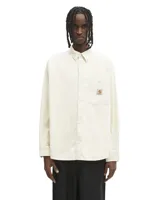 Camisa de manga larga Carhartt modelo Flint, confeccionada en pana de algodón color blanco. Presenta cuello clásico, cierre frontal con botones y un bolsillo en el pecho con el logo de la marca bordado.