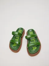 Sandalias de cuero vacuno color marrón con acabado brillante, diseño de dos tiras anchas acolchadas y plataforma baja.