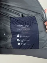 Campera azul marino con cuerpo acolchado, mangas de neopreno y cierre frontal con cremallera.