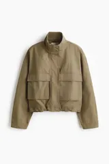 Campera corta de sarga estilo cargo en color verde militar, con cuello elevado, cierre frontal oculto con botones a presión y bolsillos delanteros de gran tamaño con solapa. Presenta diseño oversized con hombros caídos y cordón elástico ajustable en el bajo.