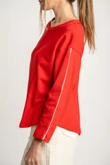 Sweater rojo de algodón con textura y corte oversize. Tiene mangas largas con dos rayas blancas en los brazos.