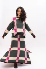 Pollera midi de tejido de punto con diseño geométrico de cuadros en tonos verde, rosa y beige. Presenta cintura elástica con cordón de ajuste y aberturas laterales en el ruedo.