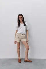 Short de tiro medio y calce ajustado, color blanco, con dobladillos en las piernas y cierre frontal con botón.