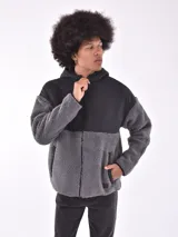 Campera con cierre frontal, capucha y diseño de bloques de color. La parte principal del cuerpo y las mangas son de tejido de borrego (teddy) color beige claro, mientras que los hombros, la capucha y los bordes son de tela negra lisa.