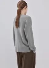 Cardigan gris de punto con escote en V, cierre frontal abotonado y mangas largas, diseño clásico y versátil.