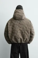 Cazadora acolchada de corte relajado con estampado jacquard. Presenta cuello subido con capucha, cierre frontal de cremallera, bolsillos frontales y puños con acabado elástico.