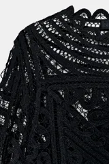 Blusa negra de manga larga confeccionada en tejido tipo crochet con intrincados patrones geométricos y florales. Presenta cuello redondo y cierre frontal con botones.