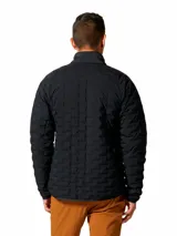 Campera técnica de Mountain Hardwear con aislamiento de plumón, diseñada con tejido elástico para mayor libertad de movimiento. Presenta cierre frontal completo, cuello alto, bolsillos laterales con cierre y diseño acolchado con patrón geométrico.