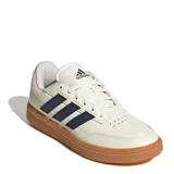 Championes urbanos Adidas Courtblock, color blanco con las icónicas tres tiras laterales en azul marino y suela de goma color caramelo. Presenta un diseño de corte bajo con detalles en rosa pálido en el talón.