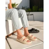 Sandalias chancletas de goma color beige con diseño texturizado en la suela, doble tira ajustable con hebillas y estilo slip-on.