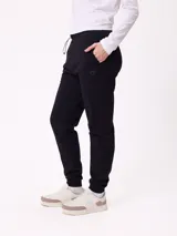 Pantalón tipo babucha de algodón y poliéster, con cintura elástica ajustable mediante cordón, bolsillos laterales y puños elásticos en los tobillos. Presenta un pequeño logo bordado en la pierna izquierda.
