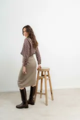 Falda midi de tiro alto confeccionada en tejido tweed con patrón de espiga en tono marrón. Presenta un diseño recto y cierre frontal con botones.